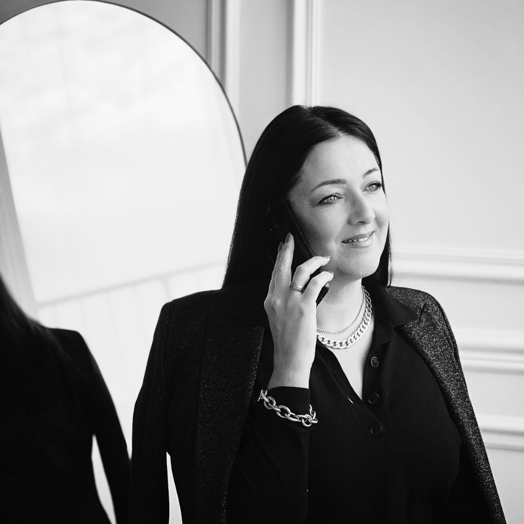 Portrait Hypnose Coach und Business-Mentorin Melanie Lohmann über "Dein Weg zu Erfolg und Selbstverwirklichung", stehend mit Telefon am Ohr, Spiegel im Hintergrund