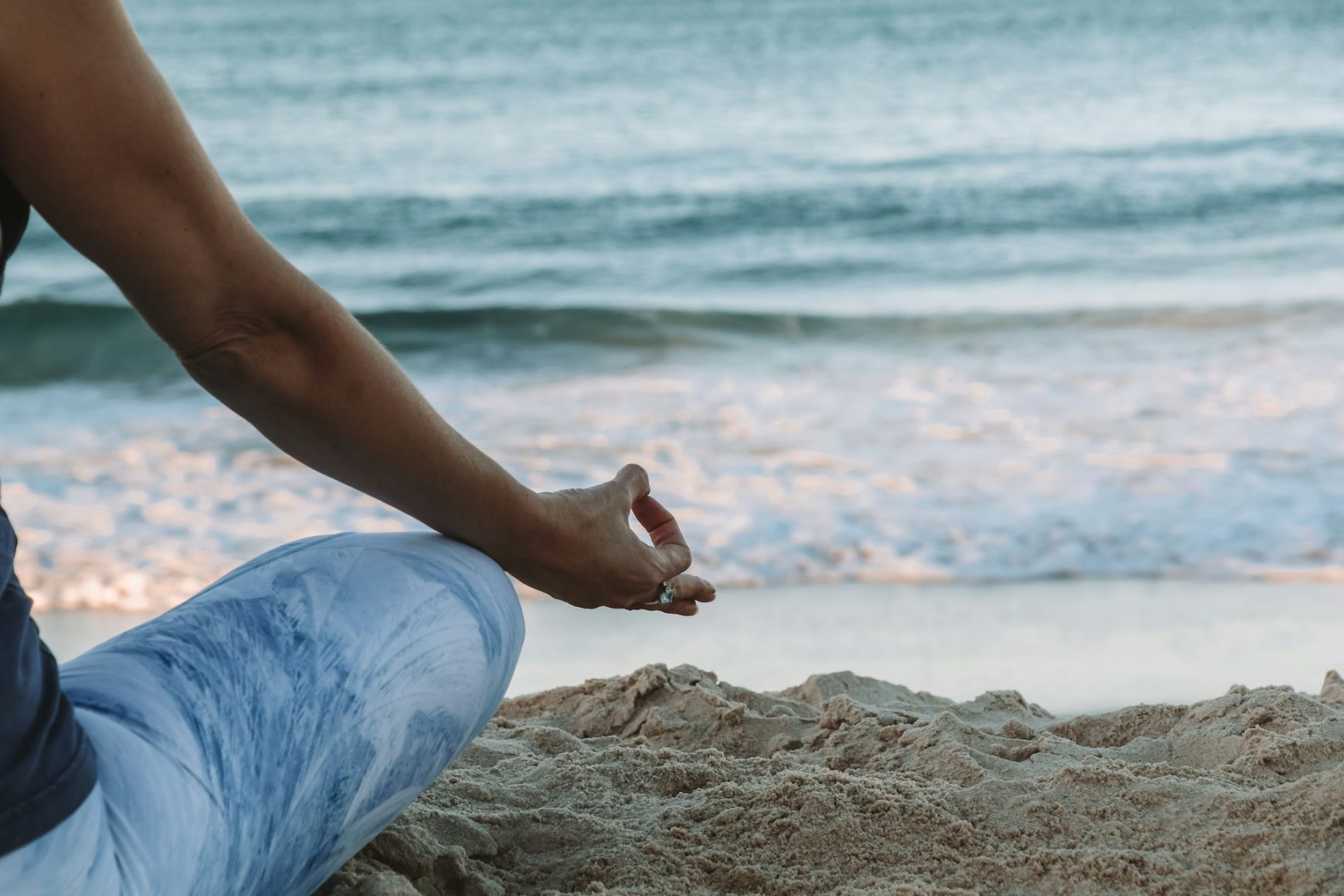 Frequenz erhöhen durch Meditation. Frau am Strand, die meditiert