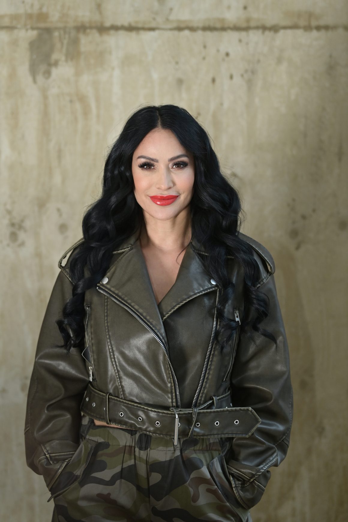 Portrait High Level Business Mentorin Gönül Pehlivan in olivgrüner Lederjacke über Social Media Interaktion